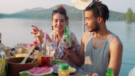 portrait of happy man and woman at lake party with friends