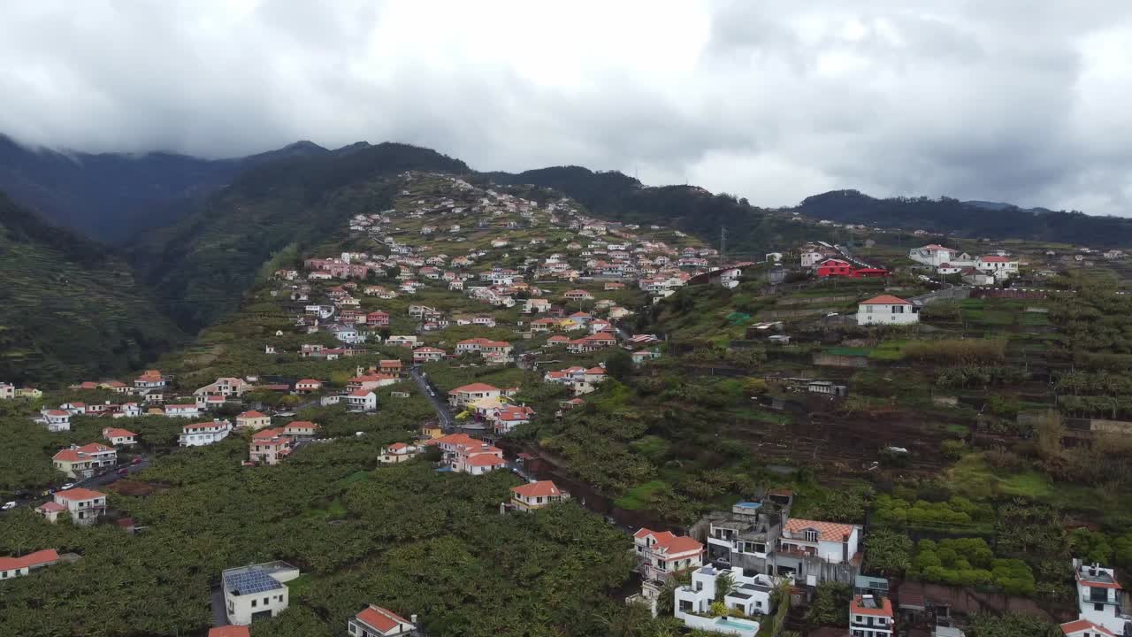 Houses nestled in the green mountains of Madeira. Scenic aerial view with dramatic landscape, perfect for travel, tourism, and nature themes