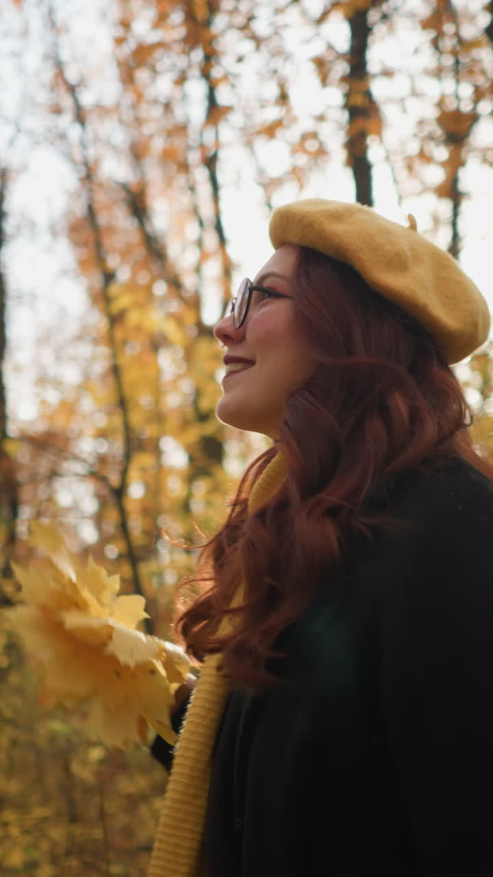 dama alegre con boina amarilla, sosteniendo hojas de otoño, baila en un bosque bañado en la luz del sol, creando una escena mágica y pintoresca rodeada de vibrantes colores de otoño