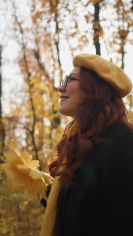joyful lady in yellow beret, holding autumn leaves, dances in a forest bathed in sunlight, creating a magical, picturesque scene surrounded by vibrant fall colors
