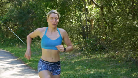 blonde female athlete running fast through park, 4k slow motion