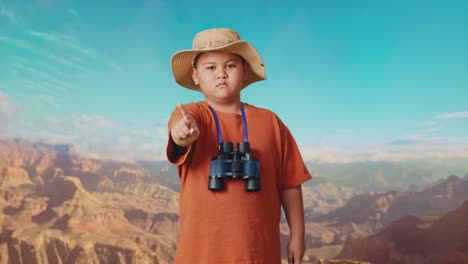 asian boy with a hat and binoculars pointing his finger towards you and shaking head waving index finger avoid offer while traveling at the top of mountain. boy researcher showing no gesture