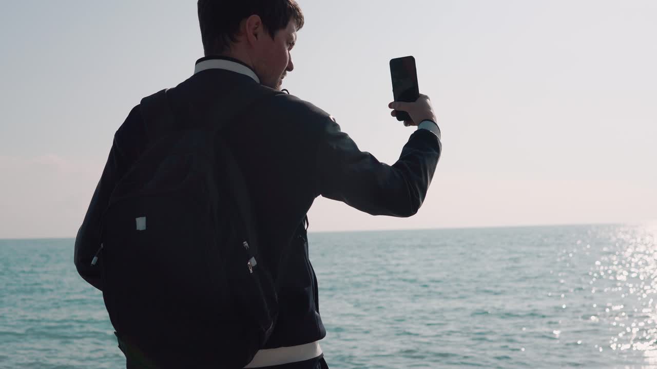 Man taking a picture of the ocean