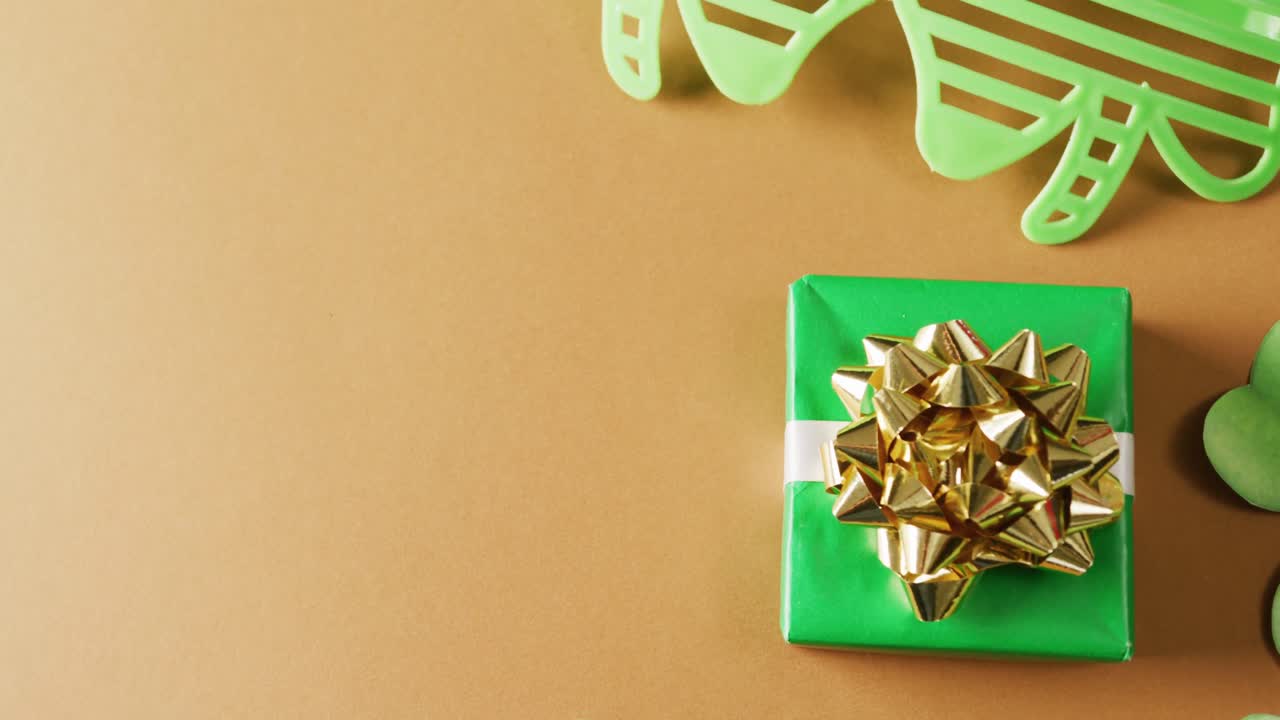 Video of st patrick's green shamrock, present and glasses with copy space on orange background