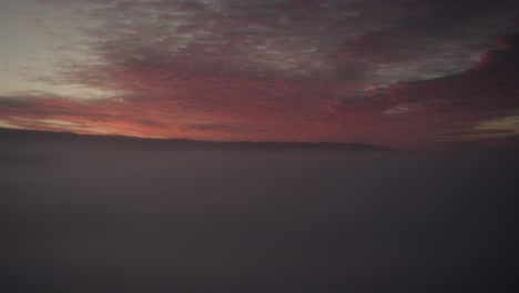 a natural spectacle: red and orange sunset over fog mist