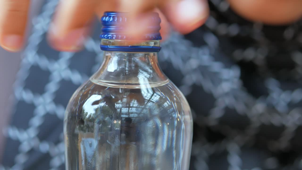 persona abriendo una botella de agua