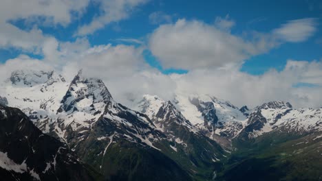 Air-flight-through-mountain-clouds-over-beautiful-snow-capped-peaks-of-mountains-and-glaciers.