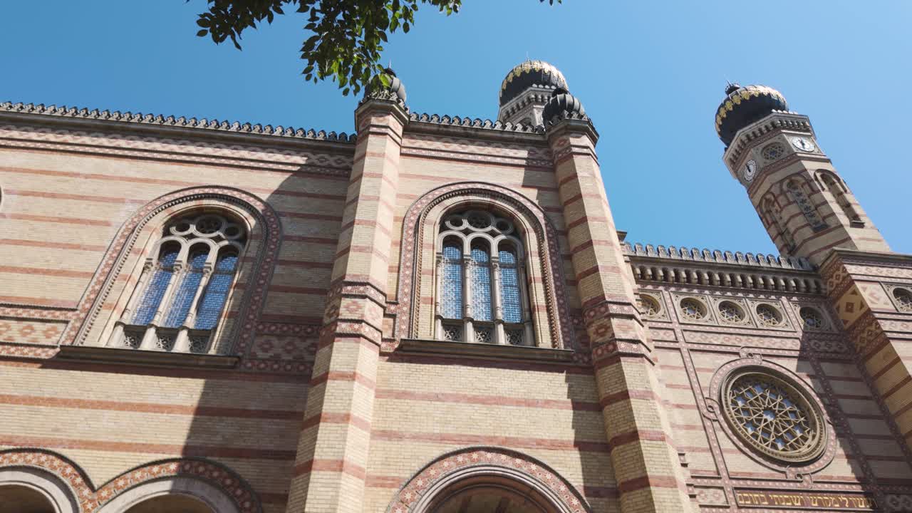 Panning across the historic exterior of the Dohány Street Synagogue in Budapest, showcasing intricate towers, arches, and detailed facade elements