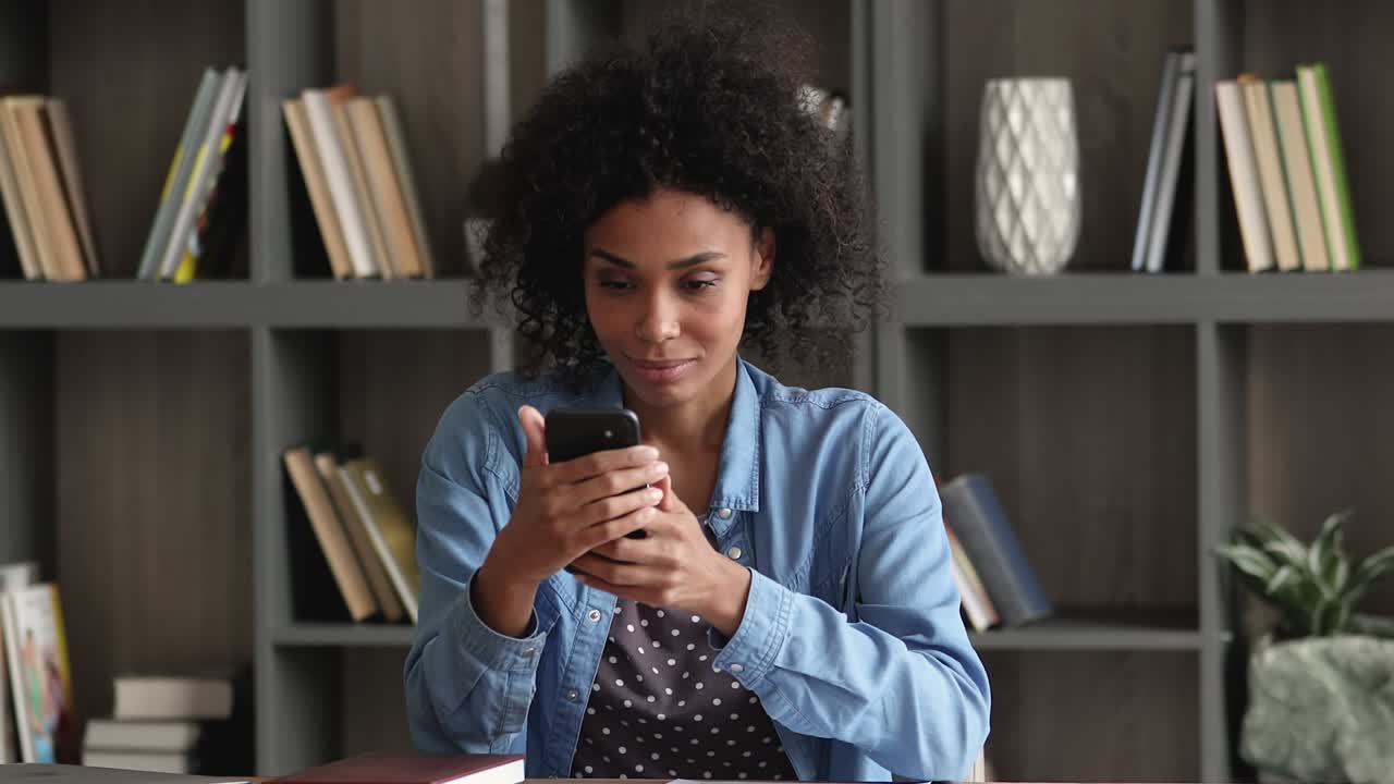 African woman holding smartphone reading great sms news feels happy