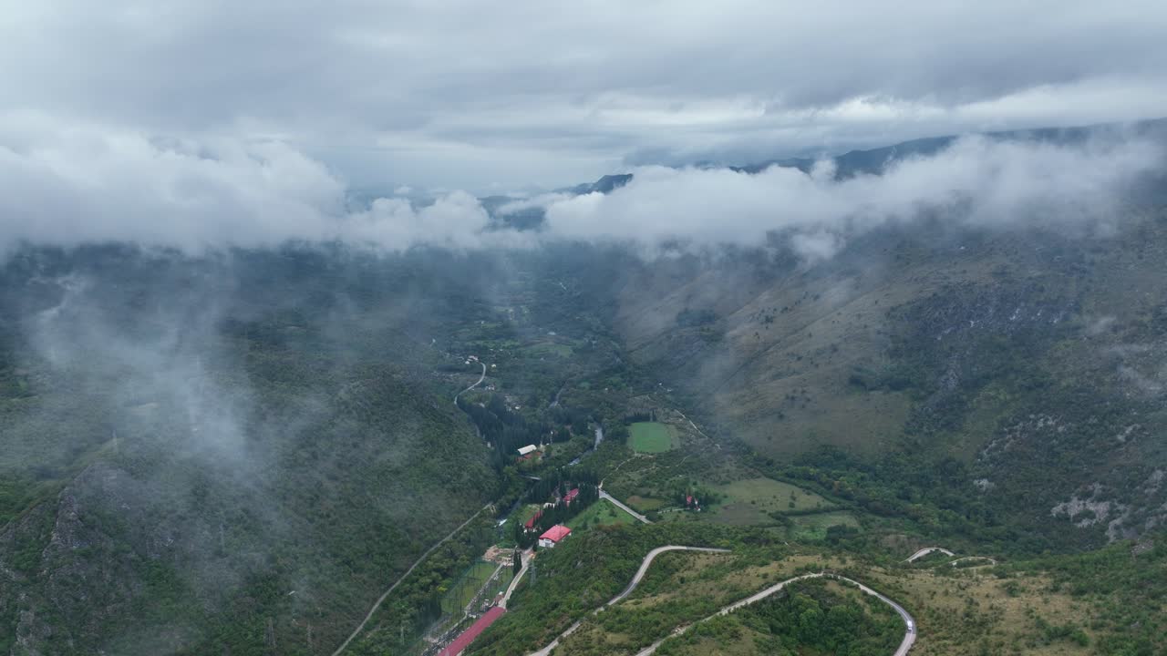 Foggy mountain landscape in Cetinje region showing remote green valleys under mist, aerial pullback