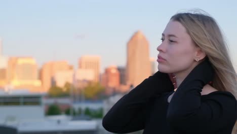 woman gazes thoughtfully from a rooftop with city skyline in the background woman gazes thoughtfully from a rooftop with city skyline in the background