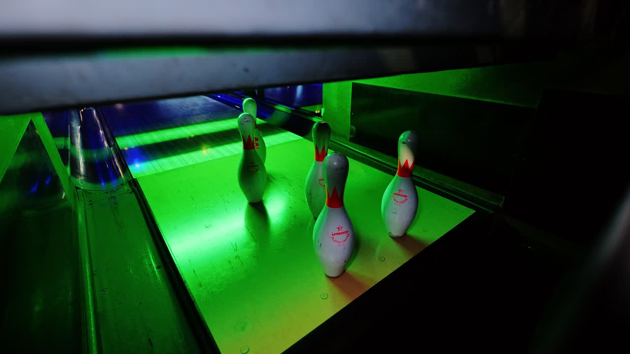 Few pins remain untouched after second ball passes by silently under neon lights