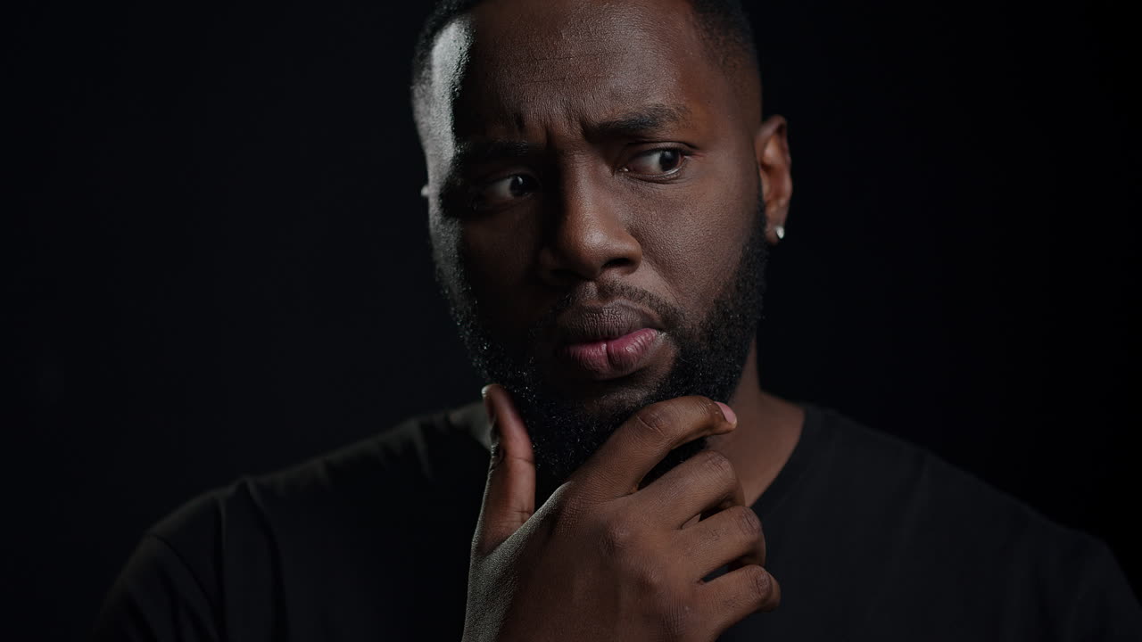 Homme afro-américain ayant une idée en intérieur. Homme rêveur posant en studio.