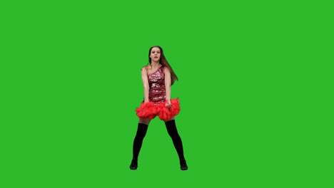 slim cheerleader with long hair dances with red pompoms. the girl performs a jubilant dance in the studio on a green screen. slow motion