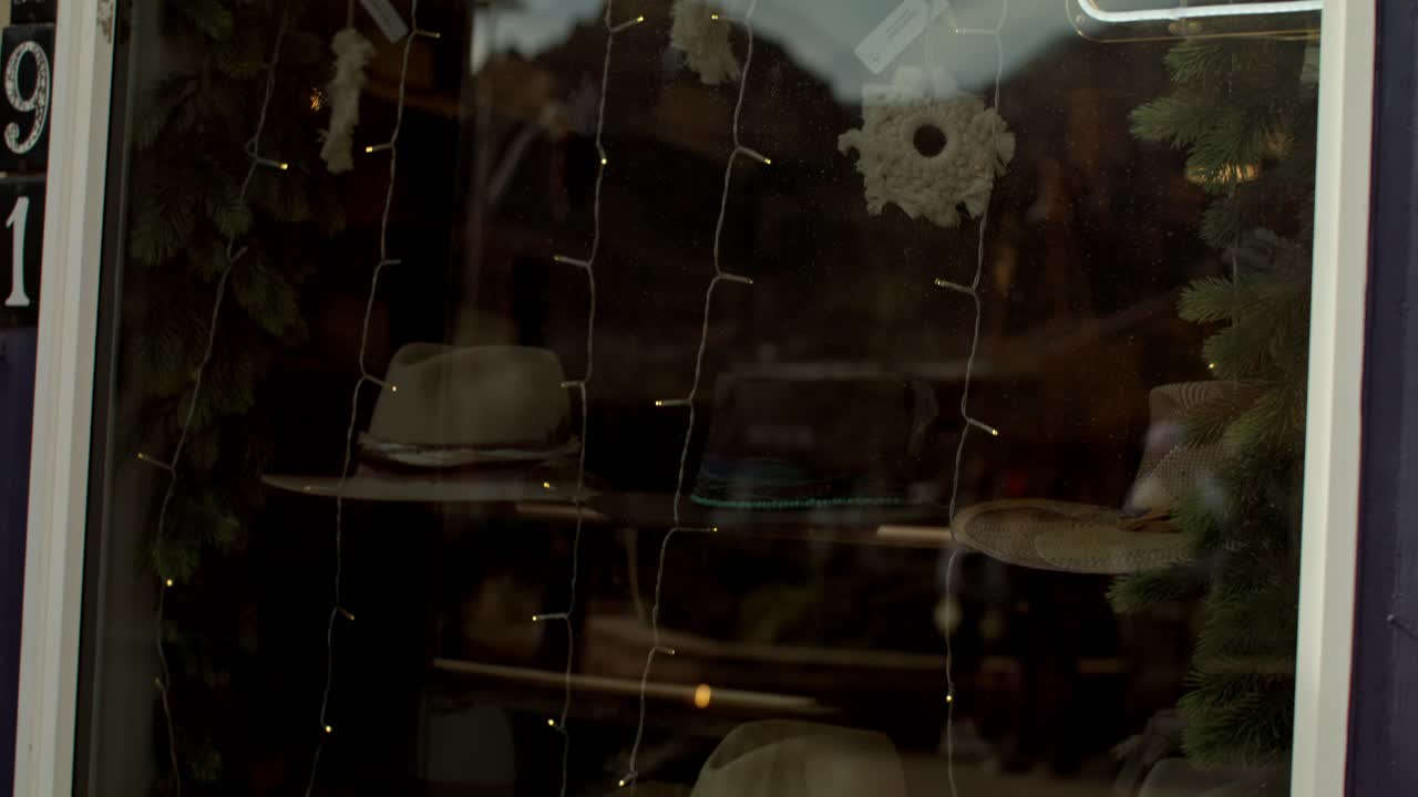 아리조나 주 세도나 시내에 있는 가게의 창문에서 카우보이 모자와 비디오가 아래로 기울어져 있습니다.