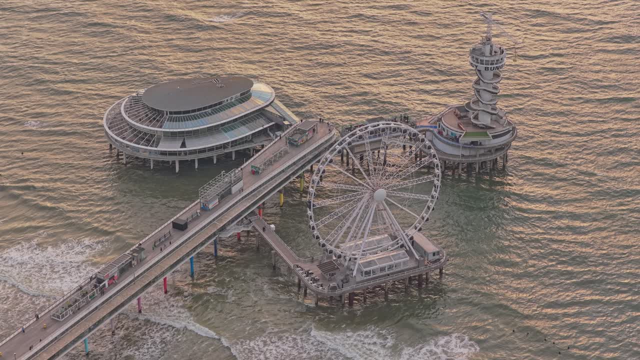 Hollanda'da Scheveningen İskelesi ve su üzerindeki Dönme Dolap'ın altın saat manzarası.