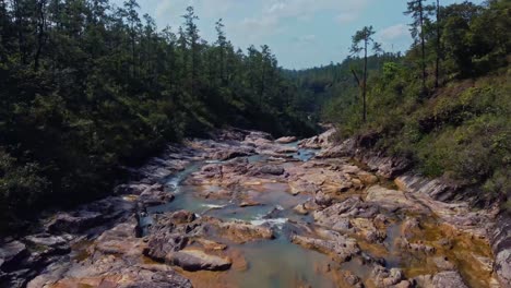 Aerial-over-the-creek-that-feeds-the-Big-Rock-Falls-in-the-Mountain-Pine-Ridge-Forest-Reserve,-Belize