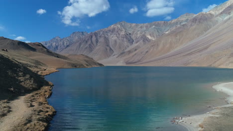 man hiking on borders of a beautiful blue lake on a sunny autumn morning