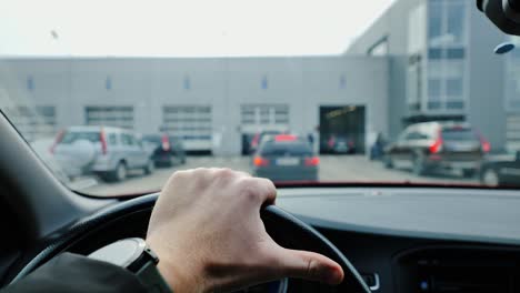 cars queue in front of inspection hall as man waits calmly behind the wheel