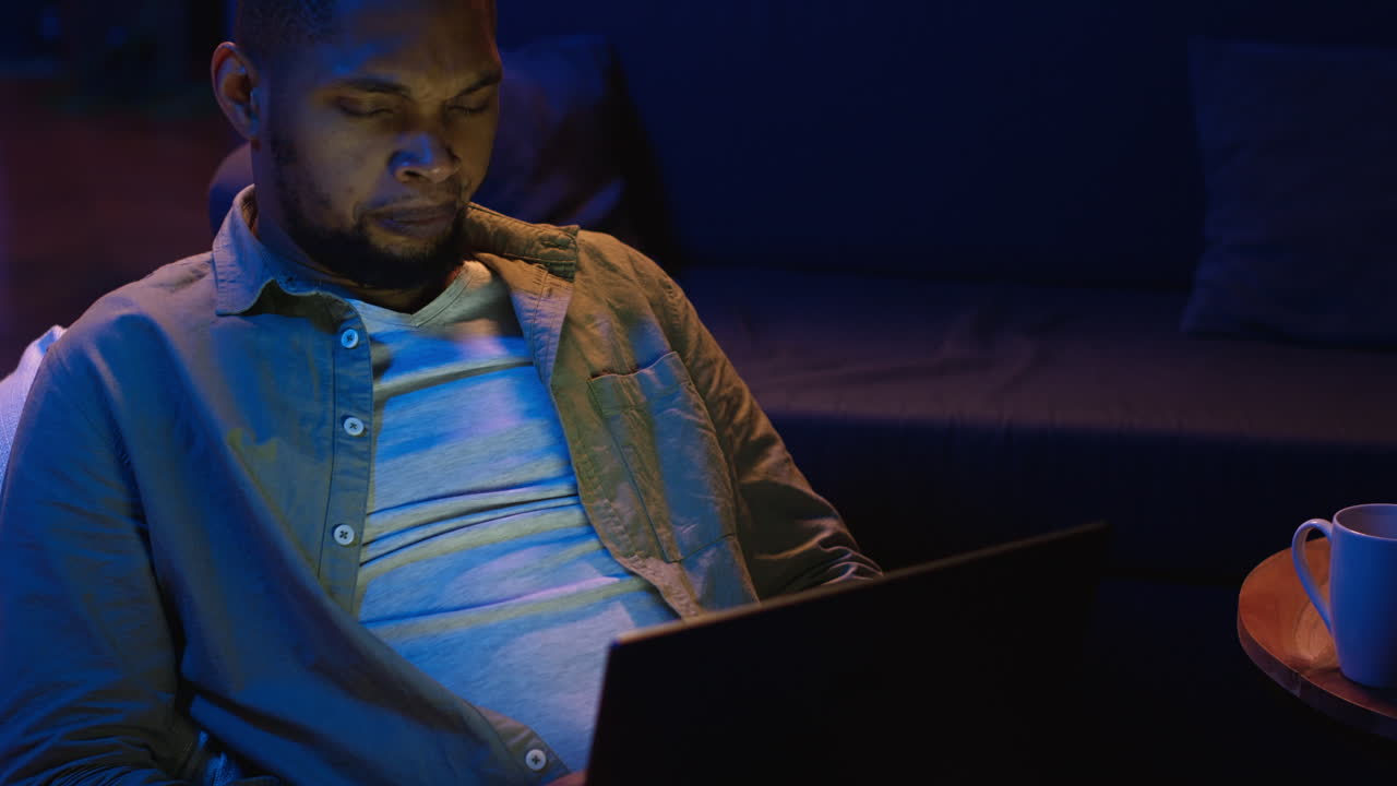 Vertical Video Adult man typing on laptop while he lays on a bean bag at home