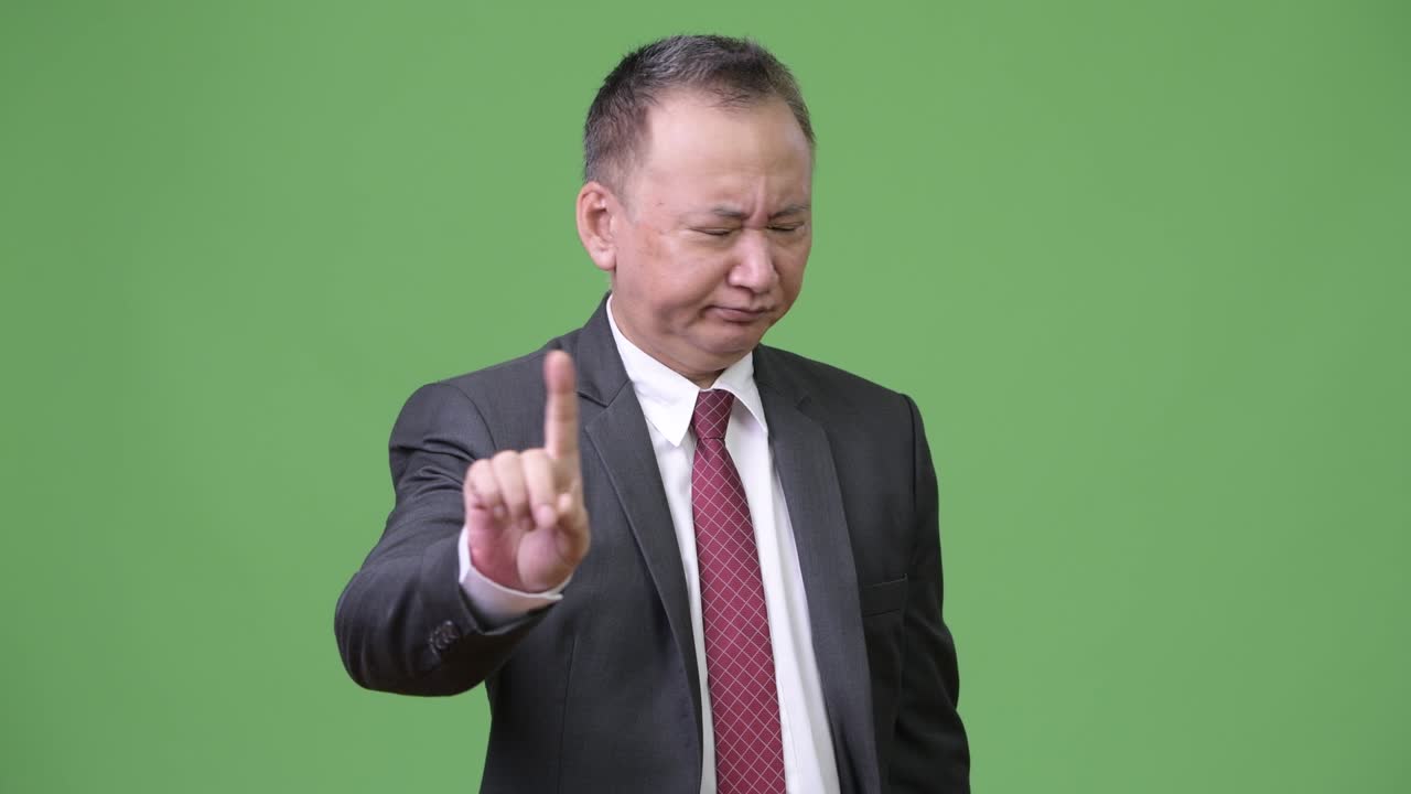 นักธุรกิจชาวญี่ปุ่นวัยกลางคนกำลังทำท่าปฏิเสธด้วยนิ้ว