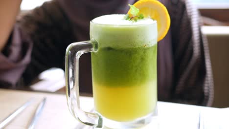 jugo verde y amarillo en capas en una taza de vidrio