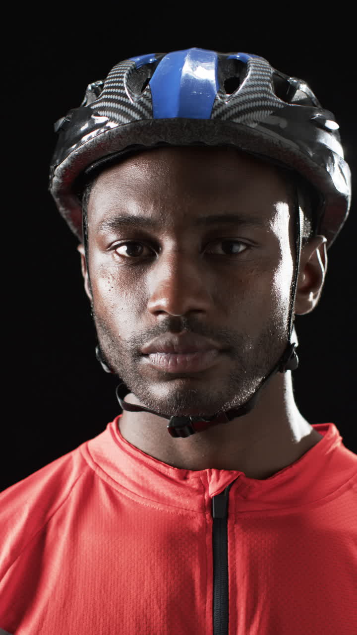 Vertical video: Strong and fit male cyclist wearing helmet and red sports jersey, looking determined