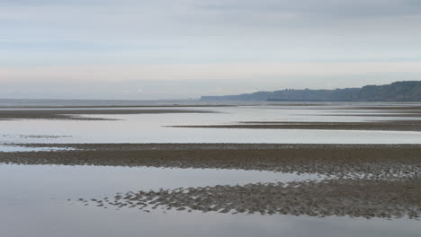 Low-tide-waves-hitting-the-deserted-Omaha-Beach-shore