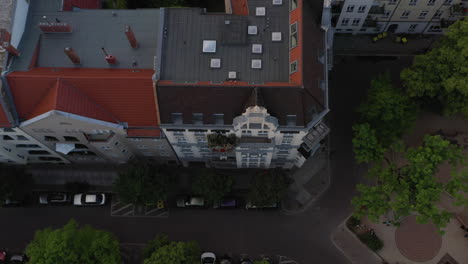 Aerial-birds-eye-overhead-top-down-ascending-view-of-multi-storey-tenement-houses-and-street-with-parked-cars.-Living-in-urban-neighbourhood.-Berlin,-Germany