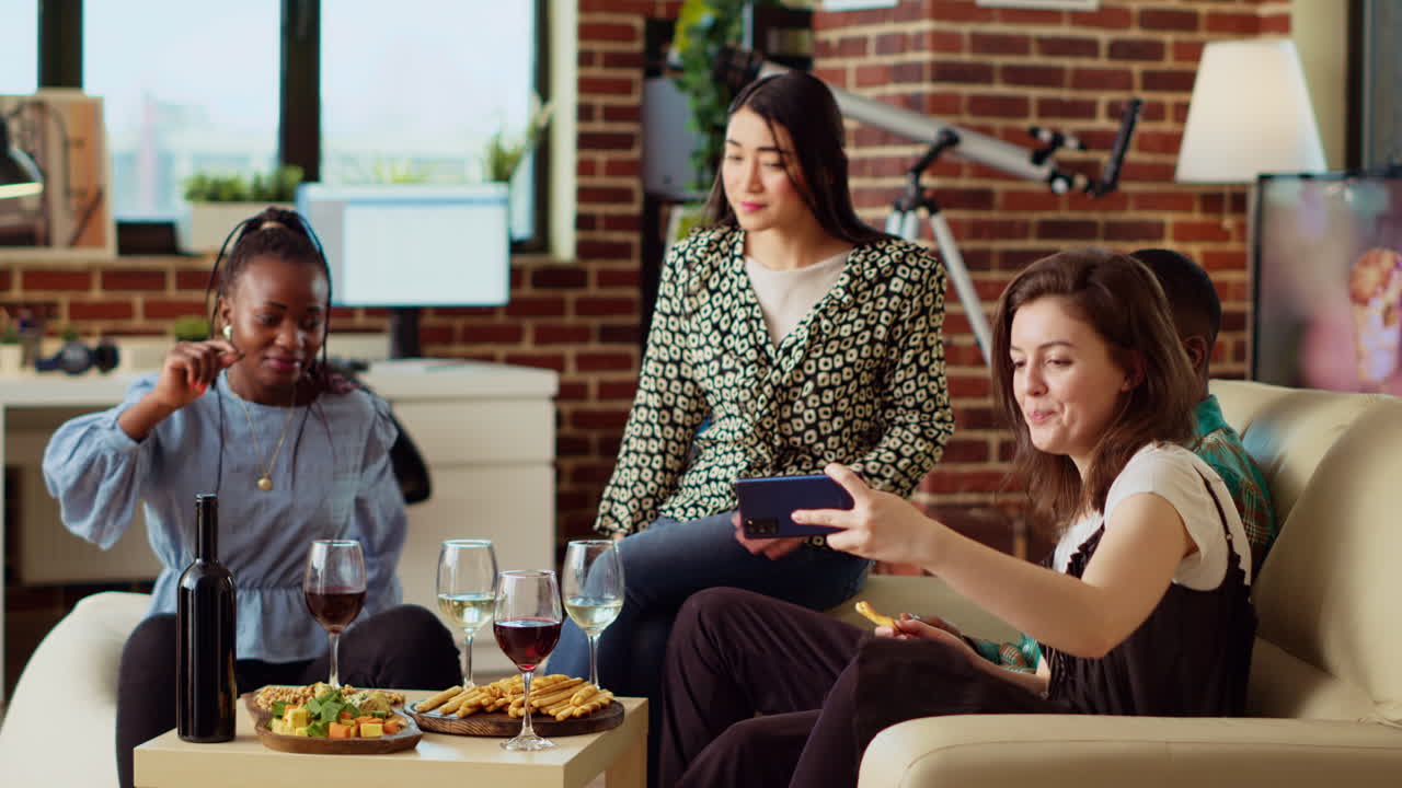 Multiracial friends taking group pictures with smartphone at apartment gathering