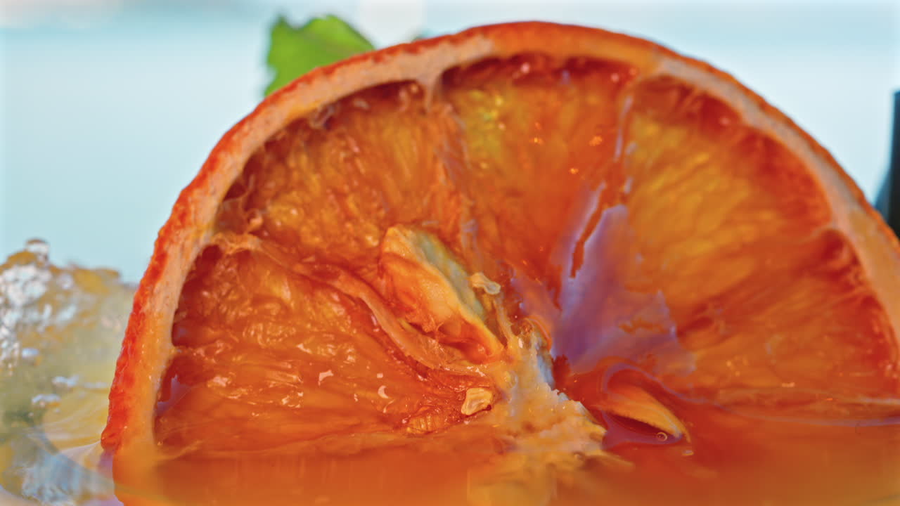 Close up of an orange cocktail on a table with a blurred view of the sea on the background