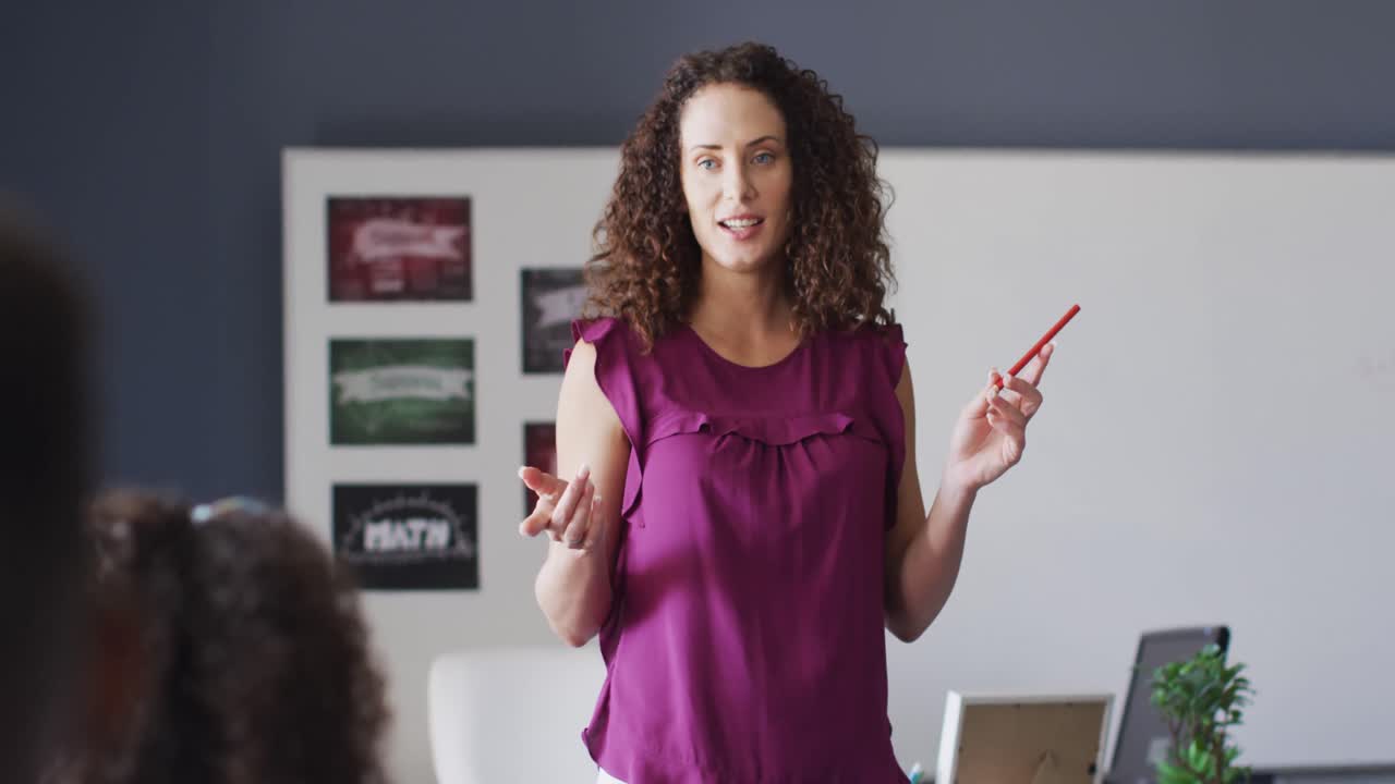 video de una maestra de escuela caucásica y niños de escuelas diversas estudiando en el aula