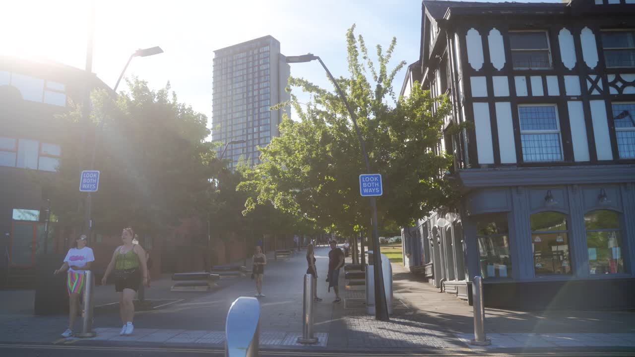 Handheld sideways shot of people in Sheffield city centre. People walking down the hill and cyclist going past.