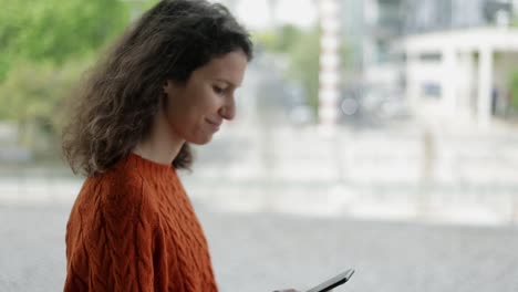 mujer feliz usando un teléfono inteligente y caminando por la calle