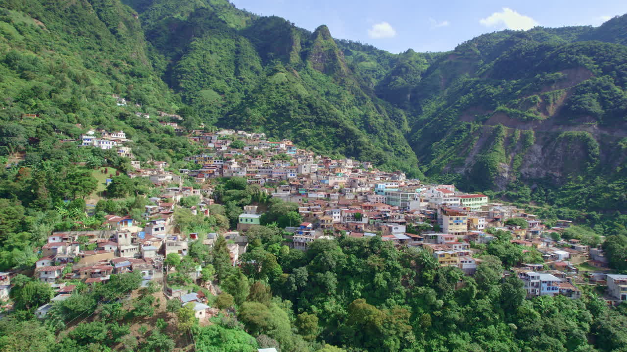 무성한 열대 우림 언덕으로 둘러싸인 중앙 아메리카 고원의 아티틀란 호수에 있는 화산 산허리 원주민 마을 산타 크루즈 라 라구나, 솔라, 과테말라의 드론 영상