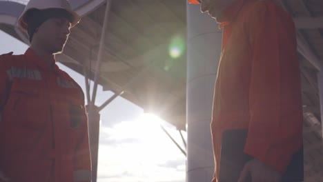 vista de cerca de dos trabajadores de la construcción en uniforme naranja y cascos dándose la mano en el objeto de construcción 1