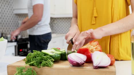 Woman-cutting-vegetables-while-man-cooking-food-in-kitchen-4k