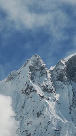 vertical snowcapped winter mountain top, pointy snowy mountains summit background with copy space for text, vertical video for social media instagram reels and tiktok, mountains in snow and blue sky