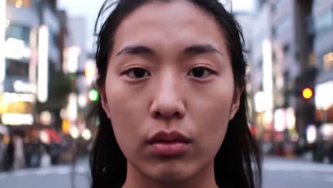 a young woman gazes directly at the camera while standing in a crowded urban street during twilight. the city lights illuminate her face, capturing the vibrant energy surrounding her.