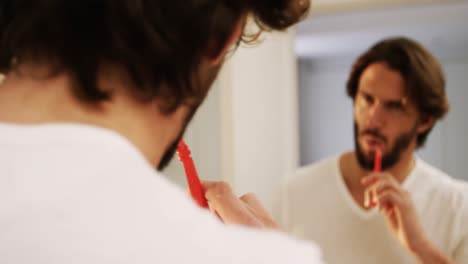 man looking in mirror while brushing his teeth in bathroom