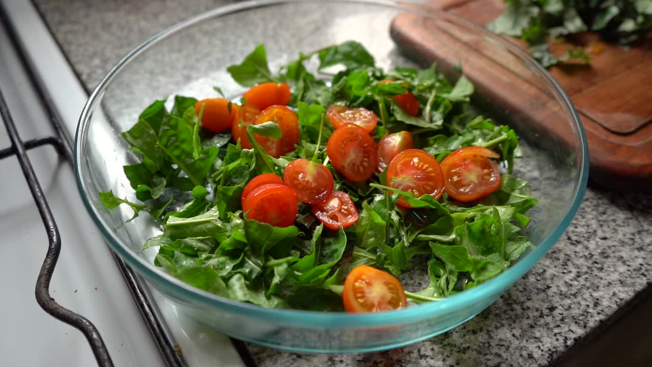 ensalada verde saludable con rodajas de tomates cherry en una ensaladera de vidrio