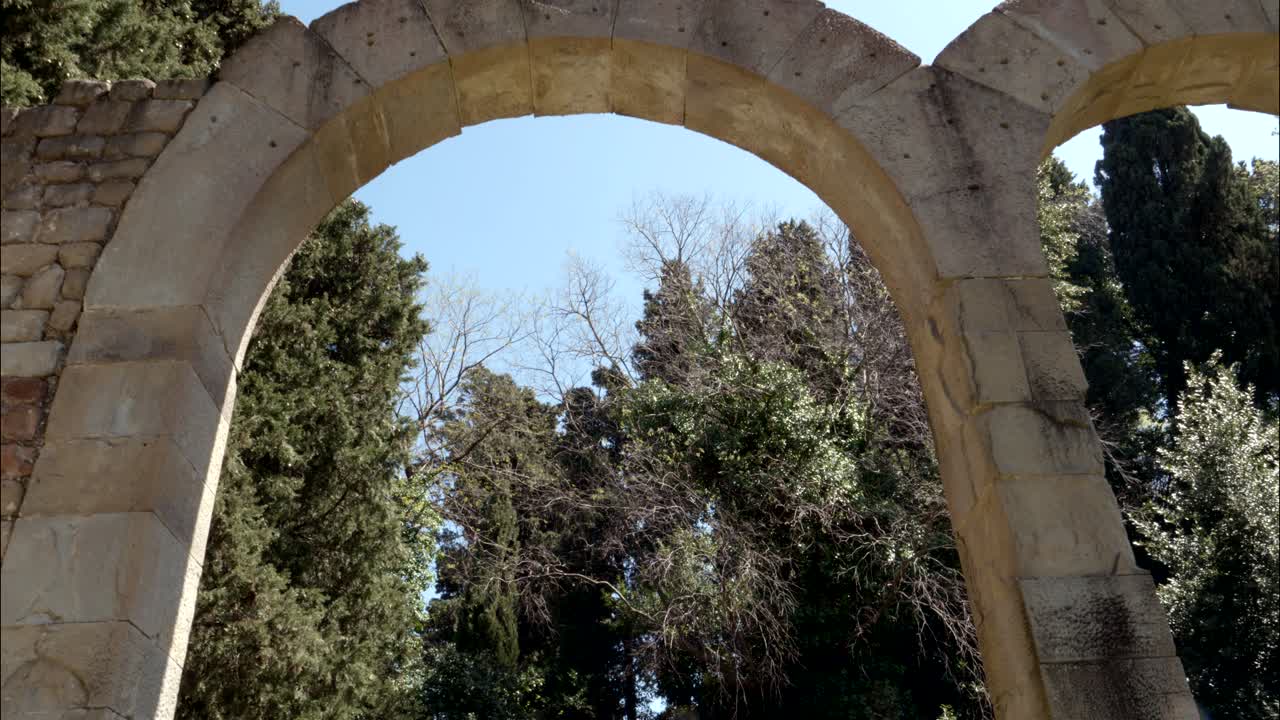 Arcata in pietra che incornicia il cielo blu e gli alberi