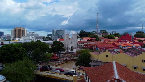 aerial forward shot of historical malaysian buildings during dramatic clouds at sky