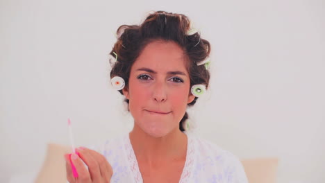 mujer satisfecha con rizos de cabello aplicando brillo