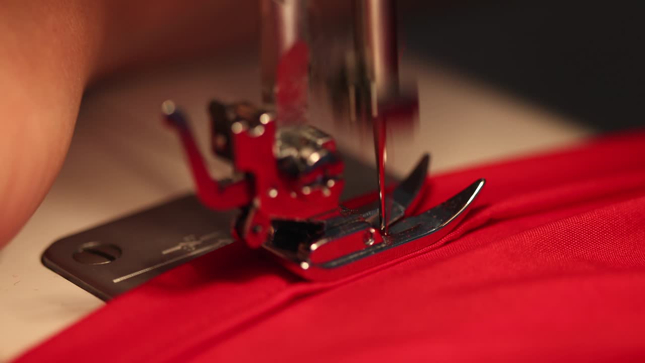 manos femeninas usan máquina de coser en vestido rojo en 4k