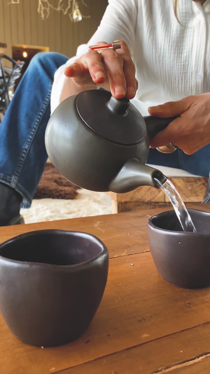 Mani di donna che versano tè caldo da una teiera in una tazza