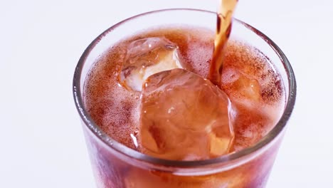 coca cola is poured into a glass from a bottle