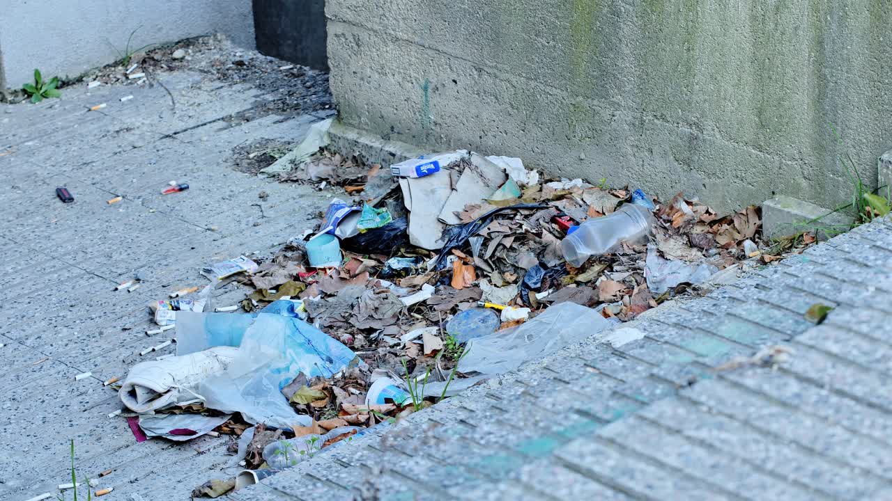 Close-up of garbage and leaves gathered against concrete wall in Prishtina city