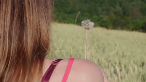 a woman blowing a dandelion outside in the green