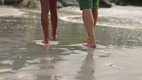 couple, legs and walking on beach water together